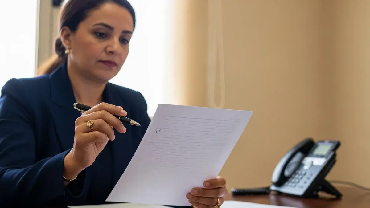 Moroccan private-school director at her desk reviewing a route log — school bus safety in Morocco